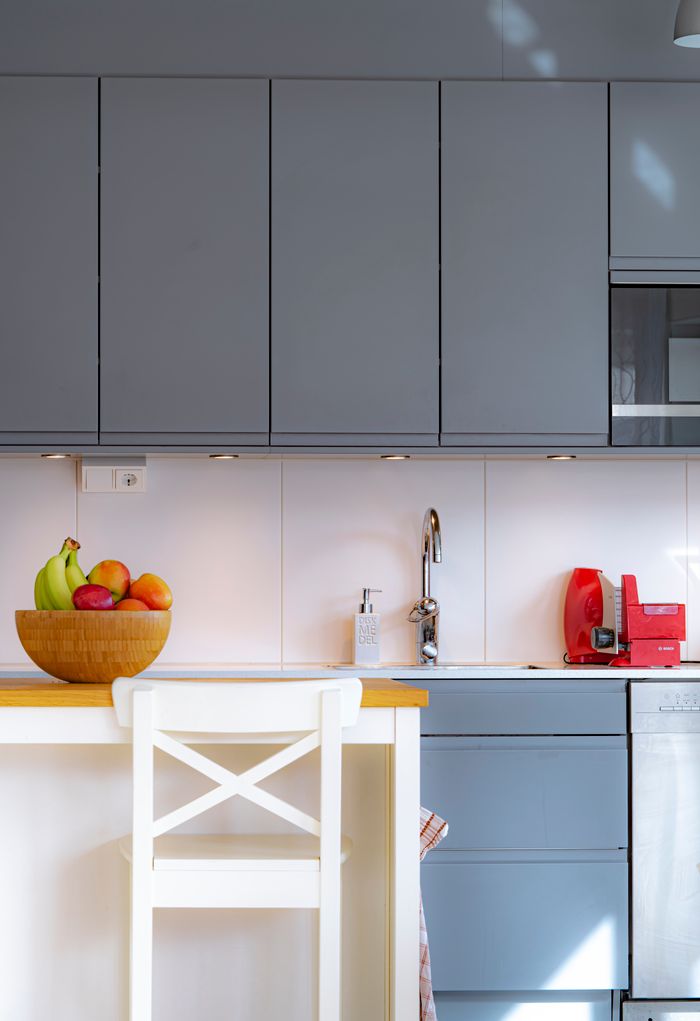 A sleek and modern kitchen interior with blue cabinets and a bowl of fruit on the countertop.